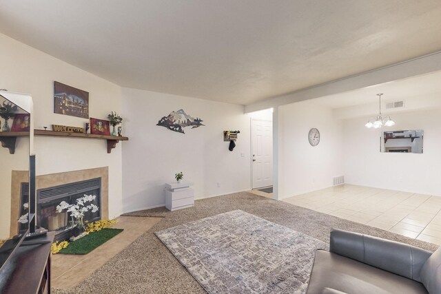 carpeted living room with a tiled fireplace and an inviting chandelier