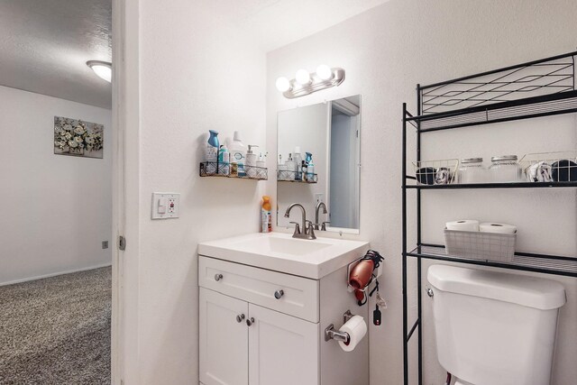 bathroom featuring toilet, a textured ceiling, and vanity