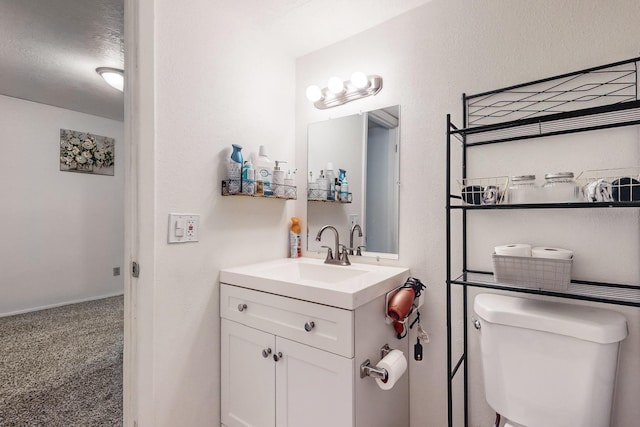 bathroom with vanity, toilet, and a textured ceiling