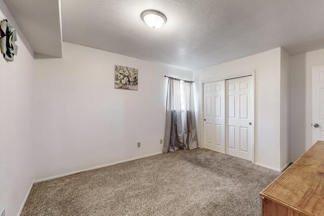 unfurnished bedroom with a closet, carpet, and a textured ceiling