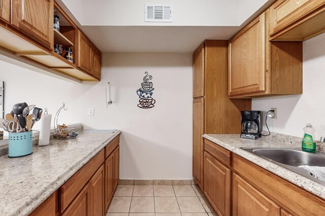 kitchen featuring sink, light tile patterned flooring, and light stone countertops