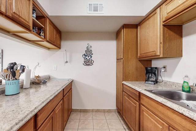 kitchen with light stone countertops, sink, and light tile patterned floors