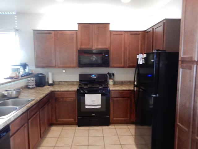 kitchen with light tile patterned floors, sink, and black appliances