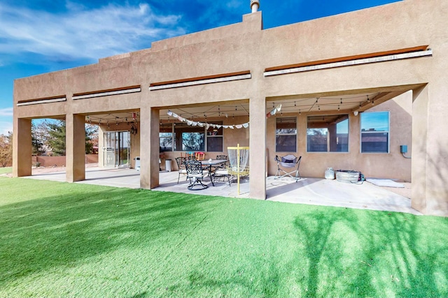 rear view of property with a lawn and a patio