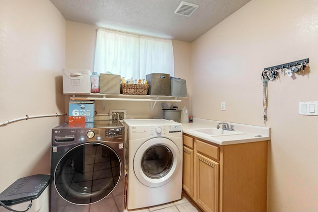 laundry area featuring cabinets, sink, washing machine and dryer, light tile patterned floors, and a textured ceiling