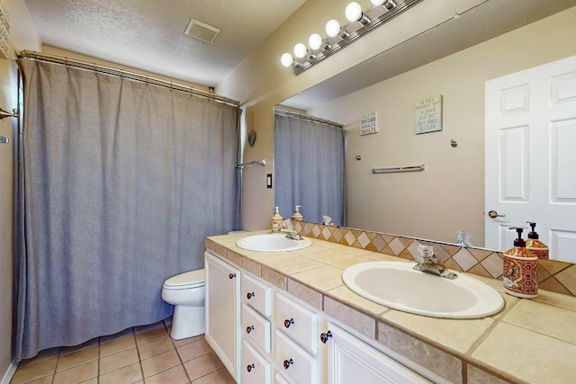 bathroom with tile patterned flooring, vanity, toilet, and a textured ceiling