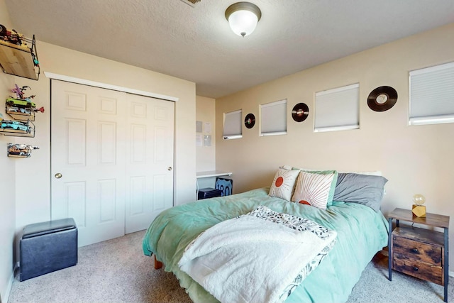 carpeted bedroom with a textured ceiling and a closet