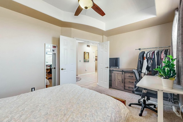 bedroom with ceiling fan, light colored carpet, and a tray ceiling