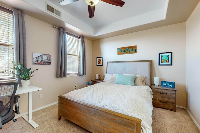 bedroom with light carpet, a raised ceiling, and ceiling fan