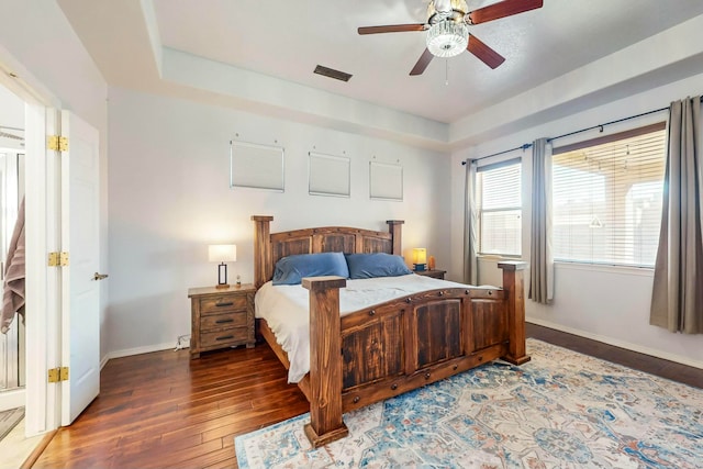 bedroom featuring dark hardwood / wood-style flooring, a raised ceiling, and ceiling fan