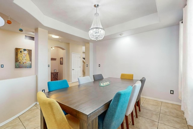 tiled dining room featuring a raised ceiling and a chandelier