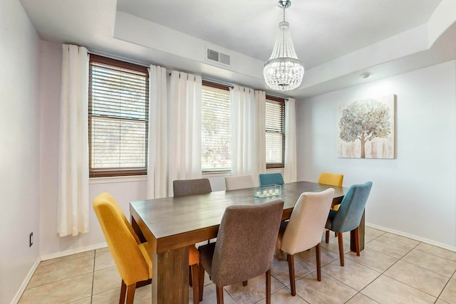 dining room featuring a tray ceiling, light tile patterned floors, and a healthy amount of sunlight