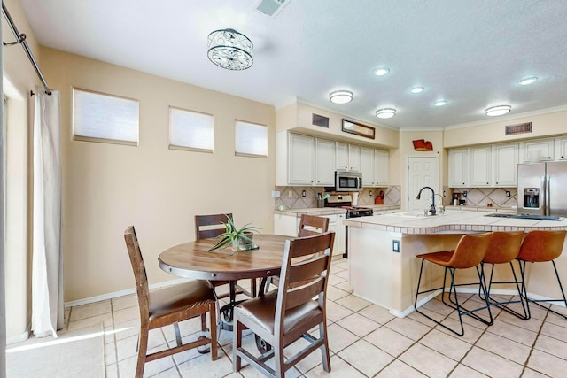 kitchen featuring tasteful backsplash, stainless steel appliances, sink, light tile patterned floors, and tile countertops