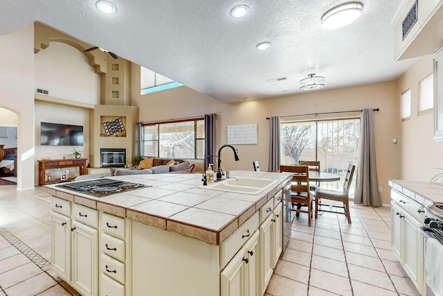 kitchen featuring a textured ceiling, sink, cream cabinets, tile counters, and stainless steel gas stovetop