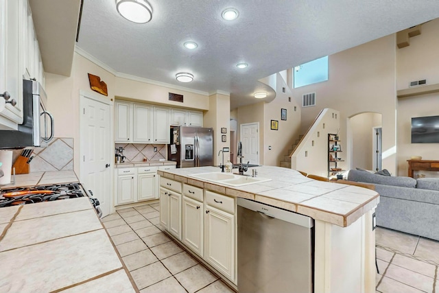 kitchen featuring sink, stainless steel appliances, tile countertops, a kitchen island with sink, and light tile patterned flooring