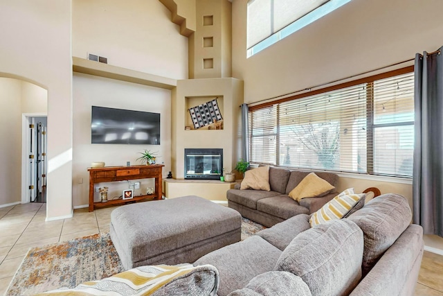 living room featuring light tile patterned floors, a towering ceiling, and a wealth of natural light