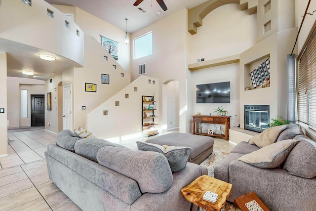 living room featuring a high ceiling, light tile patterned floors, ceiling fan, and a healthy amount of sunlight