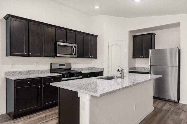 kitchen featuring appliances with stainless steel finishes, vaulted ceiling, sink, hardwood / wood-style flooring, and an island with sink