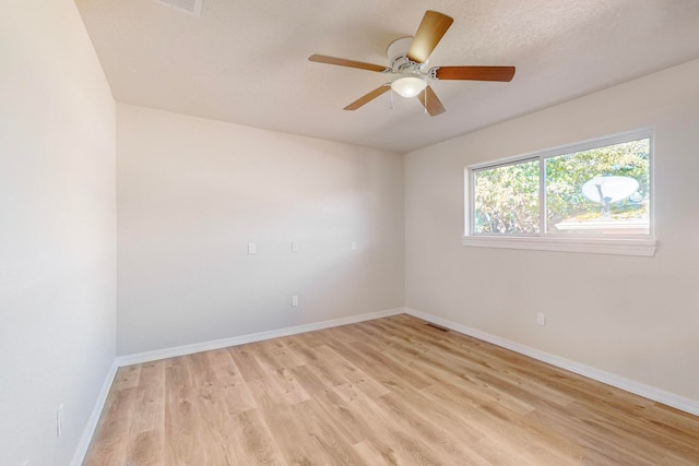 empty room with ceiling fan and light hardwood / wood-style flooring