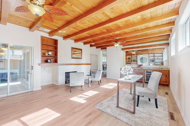 home office featuring wooden ceiling, a brick fireplace, light hardwood / wood-style flooring, built in features, and beamed ceiling