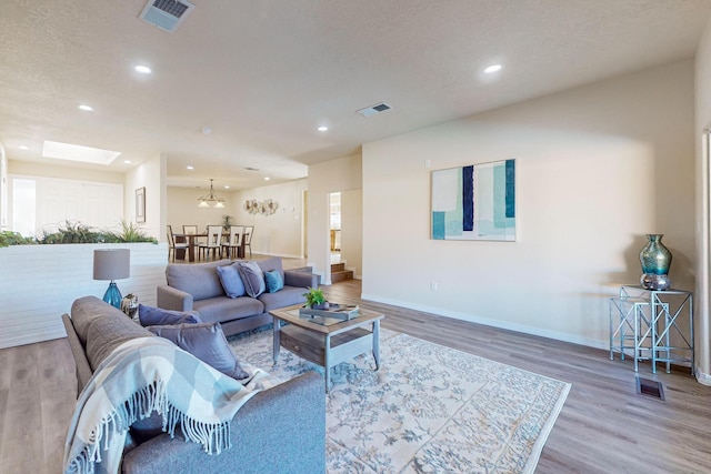 living room featuring wood-type flooring, a textured ceiling, and a skylight