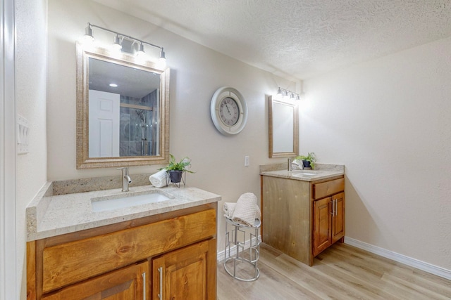 bathroom with vanity, wood-type flooring, a textured ceiling, and walk in shower