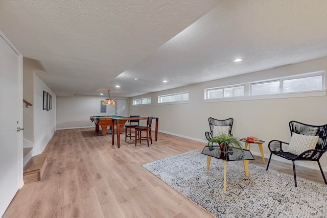 living room with a wealth of natural light, light hardwood / wood-style flooring, a textured ceiling, and billiards