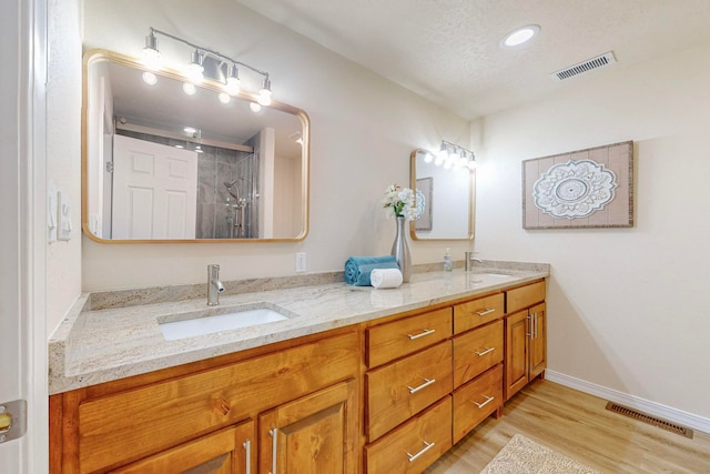 bathroom featuring a textured ceiling, vanity, hardwood / wood-style flooring, and walk in shower