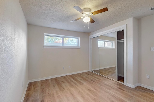 unfurnished bedroom featuring ceiling fan, a closet, a textured ceiling, and light wood-type flooring