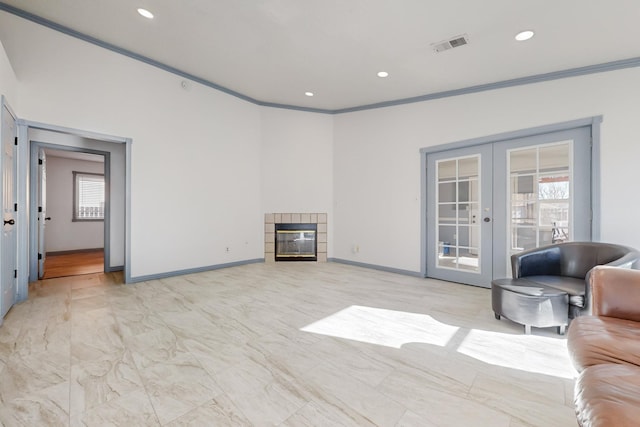 living room with a tile fireplace, crown molding, and french doors