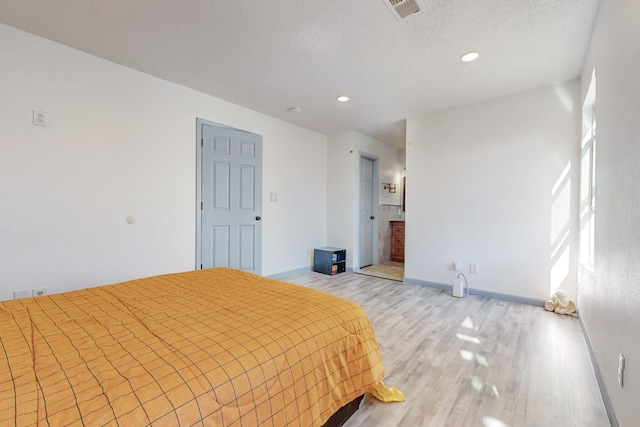 bedroom with a textured ceiling and light hardwood / wood-style flooring