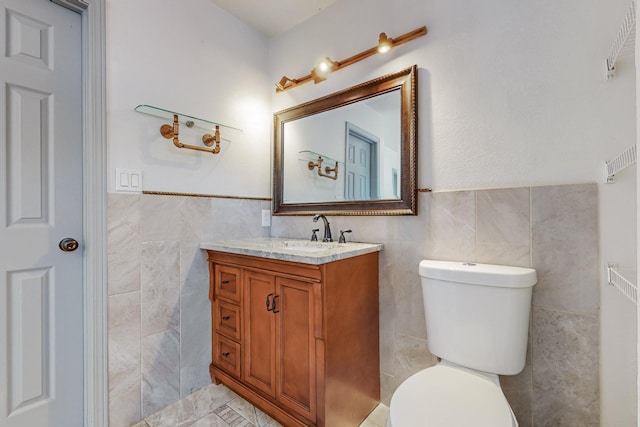 bathroom with vanity, toilet, and tile walls