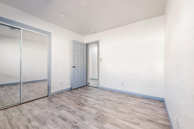 unfurnished bedroom with light hardwood / wood-style flooring and a closet