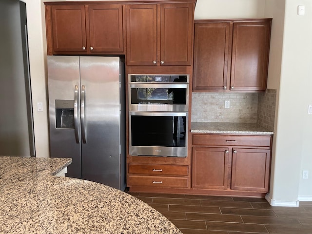 kitchen featuring backsplash, dark hardwood / wood-style floors, light stone counters, and stainless steel appliances