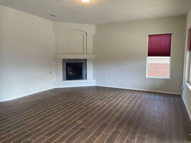 unfurnished living room featuring a textured ceiling, a fireplace, and dark wood-type flooring