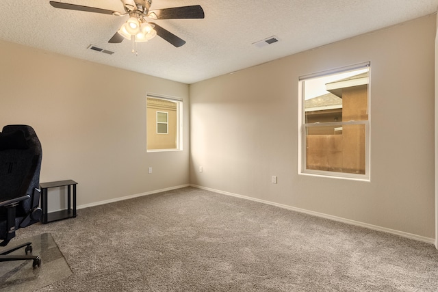 unfurnished office featuring carpet, ceiling fan, and a textured ceiling