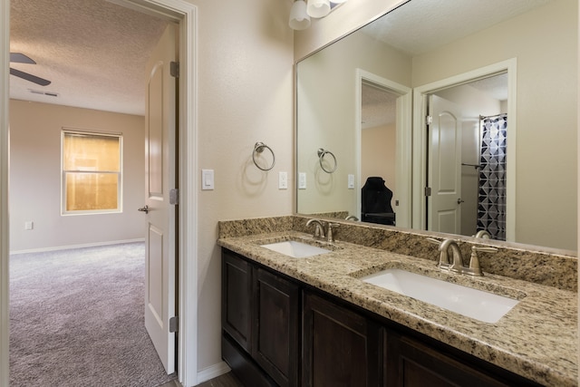 bathroom with vanity, ceiling fan, and a textured ceiling