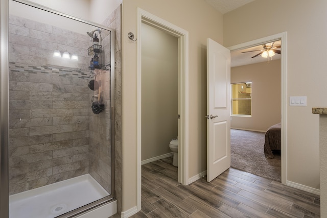 bathroom featuring hardwood / wood-style floors, ceiling fan, toilet, and a tile shower