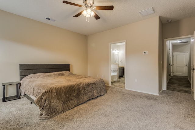 bedroom featuring light carpet, a textured ceiling, ensuite bath, and ceiling fan