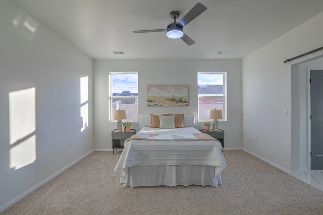 bedroom featuring a barn door, ceiling fan, and light colored carpet