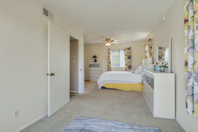 bedroom featuring ceiling fan, light colored carpet, and a textured ceiling