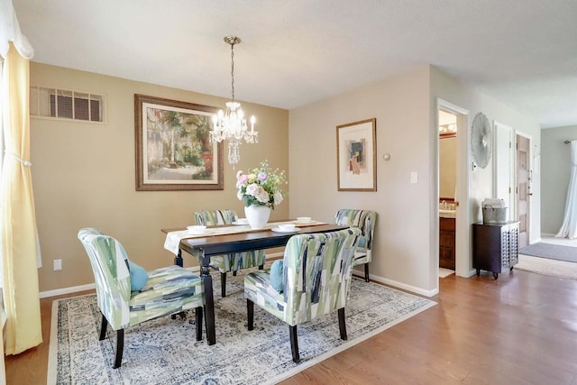 dining space featuring hardwood / wood-style flooring and an inviting chandelier