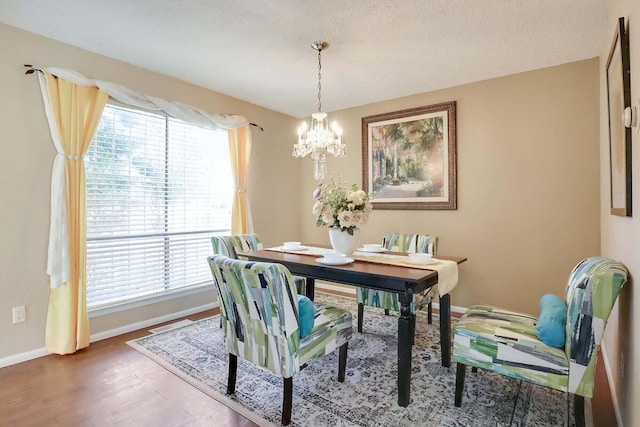 dining space featuring a notable chandelier, plenty of natural light, wood-type flooring, and a textured ceiling