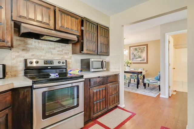 kitchen featuring dark brown cabinets, backsplash, stainless steel appliances, and light hardwood / wood-style flooring