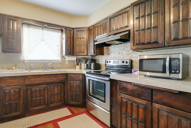 kitchen with dark brown cabinets, decorative backsplash, sink, and appliances with stainless steel finishes