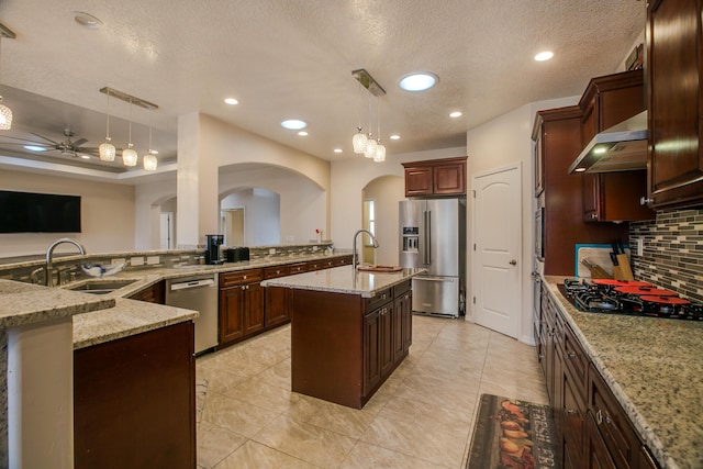 kitchen featuring pendant lighting, range hood, an island with sink, and appliances with stainless steel finishes