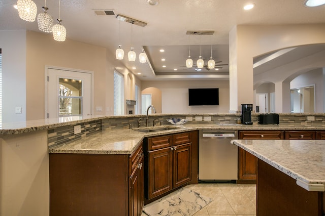 kitchen with pendant lighting, sink, dishwasher, backsplash, and a tray ceiling