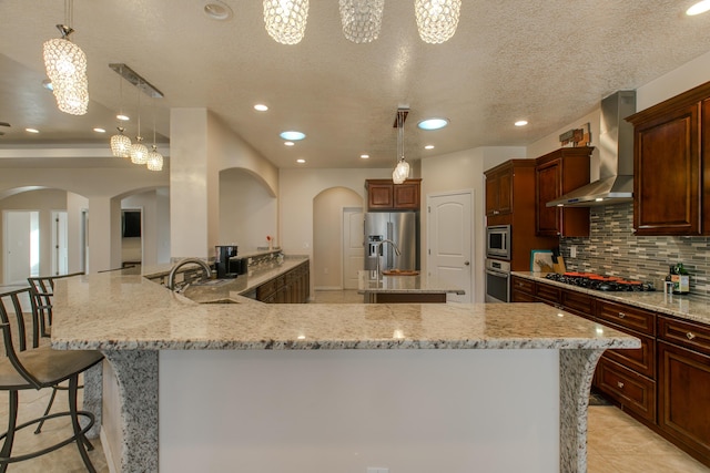 170 Esperanza Dr, Bosque Farms, NM 87068 - kitchen featuring appliances with stainless steel finishes, wall chimney exhaust hood, arched walkways, and a sink