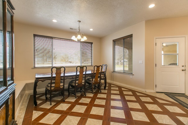 dining space featuring tile patterned flooring, a notable chandelier, and a textured ceiling