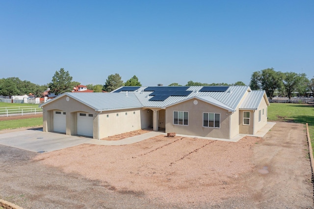 ranch-style home featuring a garage and solar panels